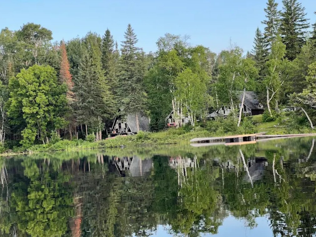 A waterfront log cabin at Normandy Lodge overlooking calm Kabenung Lake at sunset